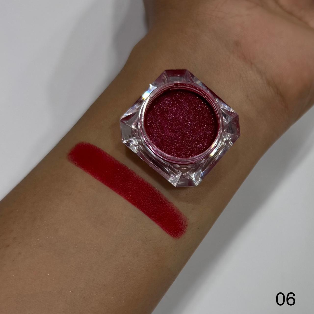 Red glittery makeup on a wrist with a swatch and container.