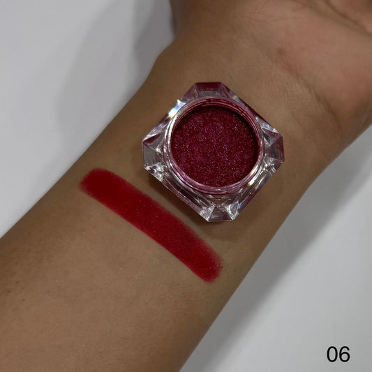 Red glittery makeup on a wrist with a swatch and container.