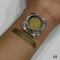 Gold glitter makeup on a wrist with a jar of glitter next to it.