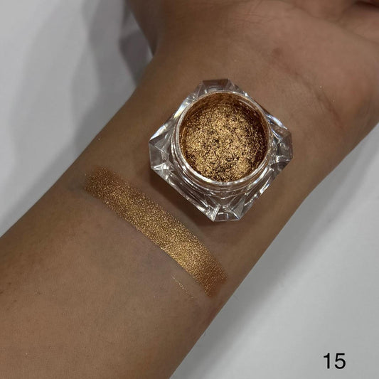 Gold glitter makeup on a wrist with a small container of glitter.