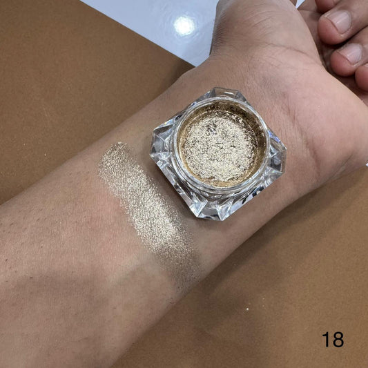 Gold glitter makeup on a wrist with a jar of glitter next to it.