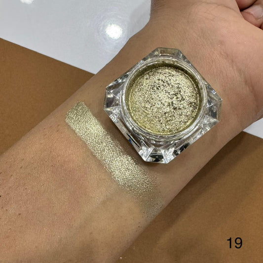 Gold glitter makeup powder in a jar on a wrist with a swatch of color.