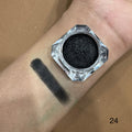 Black eyeshadow jar with swatch on wrist against a brown background